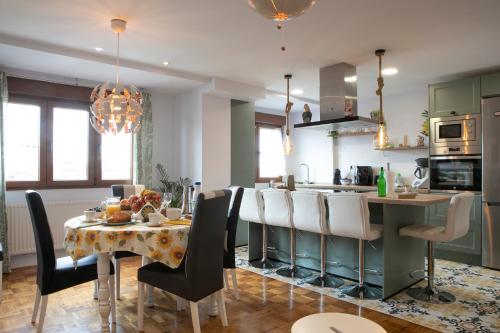 a kitchen with a table with chairs and a dining room at La Veiguela de Gijón II, con plaza de garaje y jacuzzi incluido in Gijón