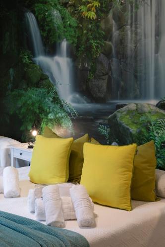 a bed with yellow pillows and a waterfall mural at La Veiguela de Gijón II, con plaza de garaje y jacuzzi incluido in Gijón