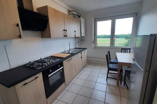 a kitchen with a stove and a sink and a table at Appart Briotin 62m2 - 2chambres in Briey