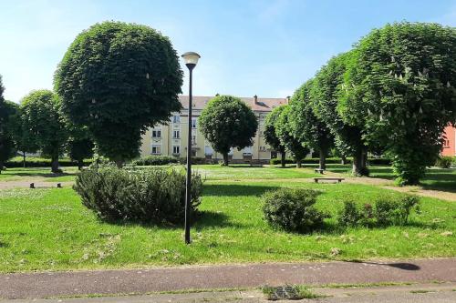 a light pole in a park with trees and a building at Appart Briotin 62m2 - 2chambres in Briey