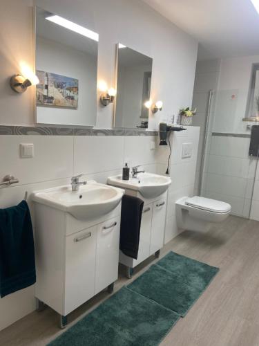 een badkamer met 2 wastafels, een toilet en een spiegel bij Ferienwohnung Haseltal in Bad Orb