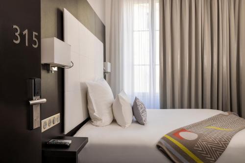 a hotel room with a bed with white sheets and pillows at Hotel 66 Nice in Nice