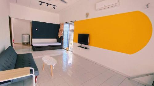 a living room with a couch and a tv on a wall at Area Indahpura or Taman Bersatu Kulai 3-4BR near AEON Airport JPO in Kulai