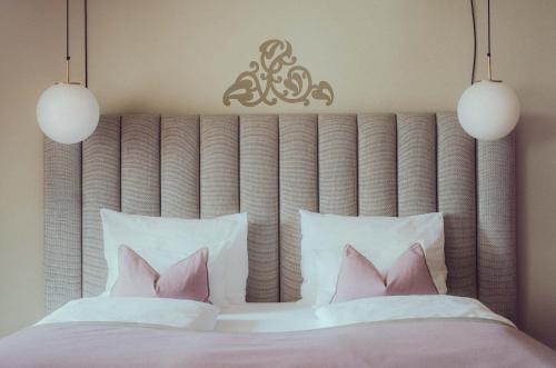 a bedroom with a large bed with pink pillows at Romantik Spa Hotel Elixhauser Wirt in Elixhausen