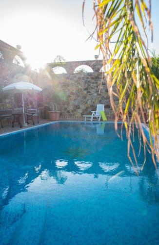 a large blue swimming pool in front of a stone wall at Castello in Valguarnera Caropepe