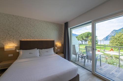 a bedroom with a bed and a large window at Hotel Bellariva in Riva del Garda