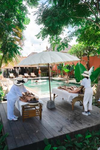 two people in hats standing next to beds by a pool at Savanna Ubud in Ubud