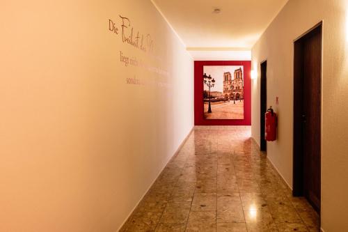 a hallway with a red door in a white wall at Hotel St. Pierre in Bad Hönningen