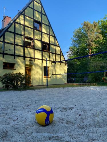 uma bola de voleibol amarela e azul na areia em frente a um edifício em Domek Marzeń em Mrzeżyno
