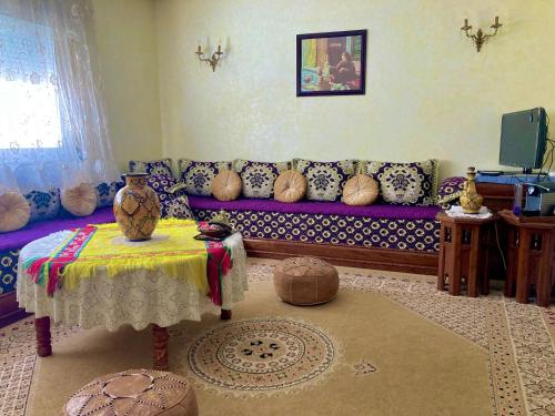 een woonkamer met een paarse bank en een tafel bij Appartement beau et familial connecté in Tanger