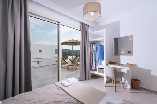 a bedroom with a bed and a desk and a balcony at Nostos Brand new Private Villa in Pitsidia