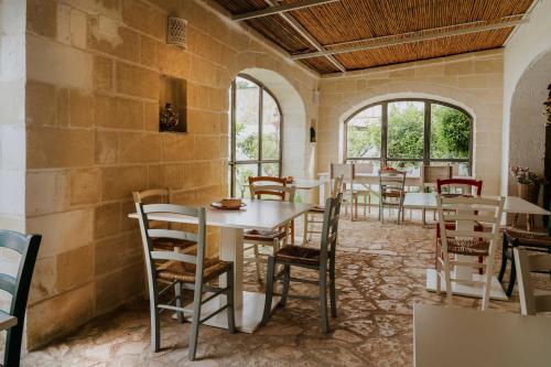 a dining room with tables and chairs and windows at Masseria della Piana in Villanova di Ostuni