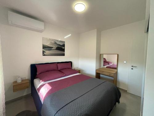 a bedroom with a bed with pink pillows and a mirror at Villa Narona in Medulin
