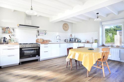 une cuisine avec des armoires blanches et une table avec des chaises dans l'établissement Le Cottage des Pêcheurs - Charmante Maison pour 6, à Portbail