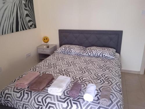 a bed with a black and white comforter and towels on it at Xylophagou Rest and Relax 3 Ayia Napa Larnaca 1 bedroom apartment in Xylophaghou