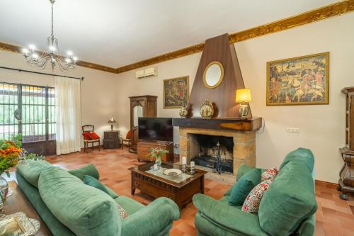 a living room with green couches and a fireplace at Casa rural Azahares de Marchena in Marchena