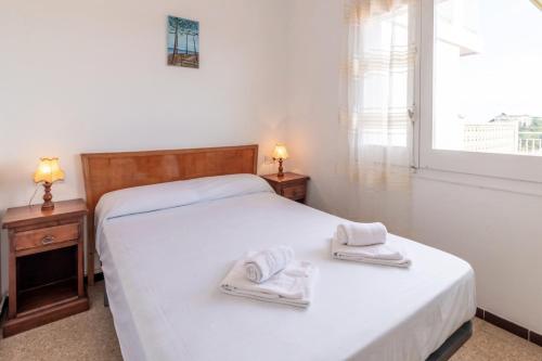 a bedroom with a white bed with towels on it at La Farella 63 apartamento con terraza y vistas in Girona
