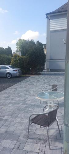 a patio with a table and two chairs and a car at Pension Rainbow*** in Karlovy Vary