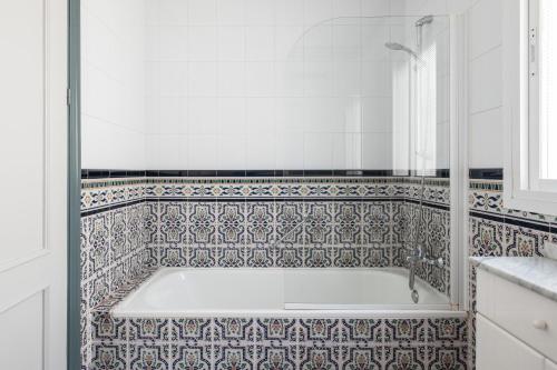 een badkamer met een bad en een betegelde muur bij Villa Mimosa in Cómpeta