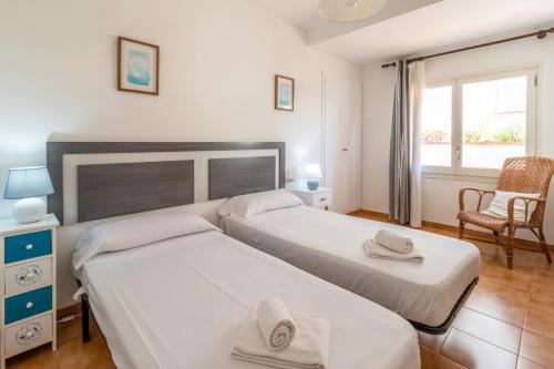 Un dormitorio con dos camas y una silla y una ventana. en La Farella La Coma 65 Apartamento con vistas mar, en Girona