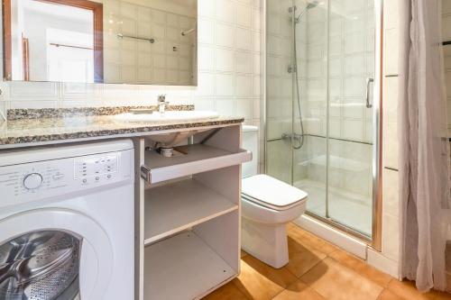 Un baño con lavadora y un inodoro. en La Farella La Coma 65 Apartamento con vistas mar, en Girona