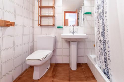 ein weißes Badezimmer mit Toilette und Waschbecken in der Unterkunft La Farella-Coma 66 - Apartamento con piscina comm in Girona