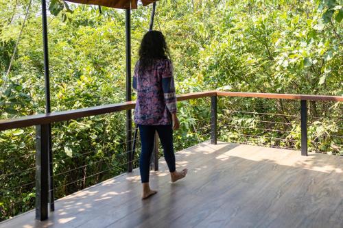 a woman standing on a wooden deck with an umbrella at Cabo Serai in Canacona