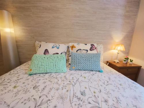 Bett mit blauer und weißer Bettwäsche und Kissen in der Unterkunft ALOJAMIENTO MIRABUENOS in Aranda de Duero