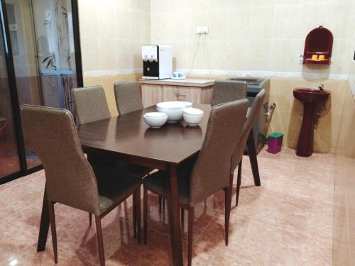 a wooden table with chairs and bowls on it at Area Indahpura or Taman Bersatu Kulai 3-4BR near AEON Airport JPO in Kulai