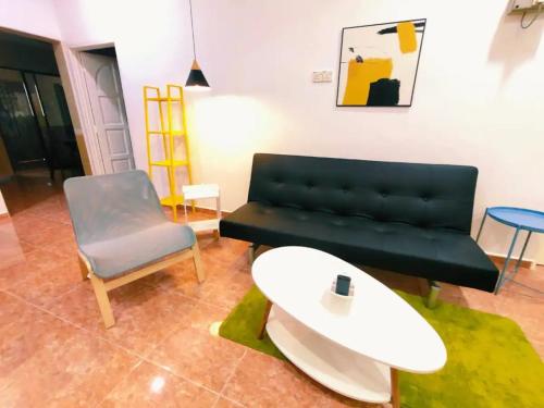 a living room with a black couch and a chair at Area Indahpura or Taman Bersatu Kulai 3-4BR near AEON Airport JPO in Kulai