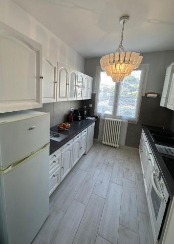 une cuisine avec des armoires blanches et des comptoirs noirs dans l'établissement Maison de ville plein centre, 3 étoiles, à 200m de la plage, parking privé, WIFI, à Royan