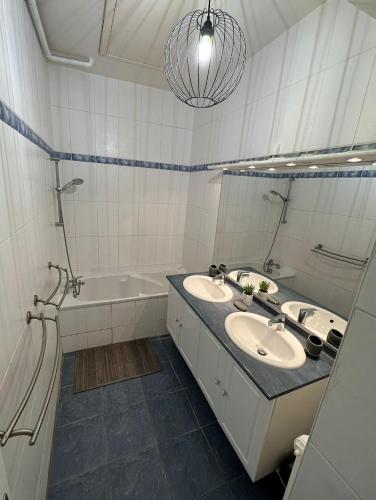 La salle de bains blanche est pourvue de 2 lavabos et d'une baignoire. dans l'établissement Maison de ville plein centre, 3 étoiles, à 200m de la plage, parking privé, WIFI, à Royan