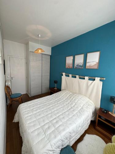 - une chambre avec un grand lit blanc et un mur bleu dans l'établissement Maison de ville plein centre, 3 étoiles, à 200m de la plage, parking privé, WIFI, à Royan