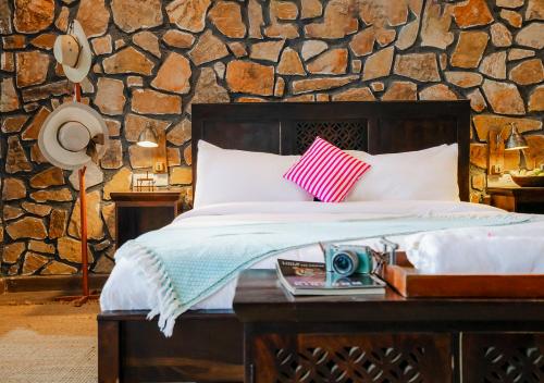 a bedroom with a bed and a stone wall at Moustache Ranthambore Luxuria in Sawāi Mādhopur