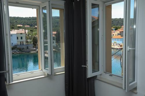a room with three windows with a view of the water at Exceptional Apartment Juniper, FIRST ROW TO THE SEA in Božava