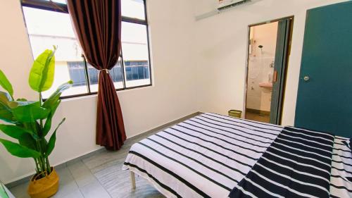 a bedroom with a striped bed and a plant at Area Indahpura or Taman Bersatu Kulai 3-4BR near AEON Airport JPO in Kulai