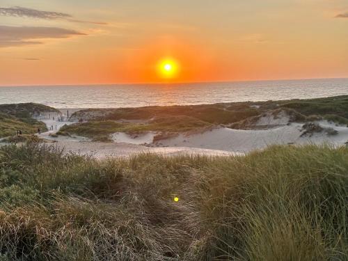 a sunset on the beach with the sun setting over the ocean at Luxury home in quiet neighbourhood near beach in The Hague