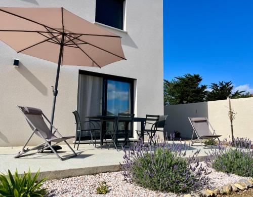 un patio con tavolo, sedie e ombrellone di La Maison Louis - moderne & familiale a Lapalme