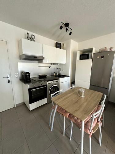 La cuisine est équipée d'une table, d'une cuisinière et d'un réfrigérateur. dans l'établissement Le Lironde - charmant F2, à Montpellier