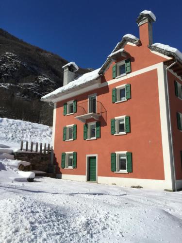a building with snow on the ground in front of it at MyVerzasca Resort Casa Rossa in Brione