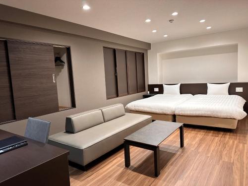 池田的住宿－雷夫特大阪機場酒店，一间卧室配有两张床、一张沙发和一张桌子