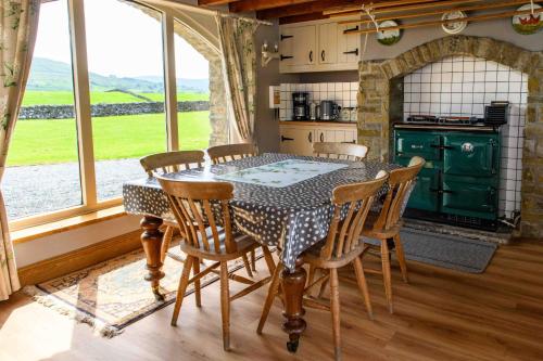 a kitchen with a table with chairs and a green oven at Finest Retreats - Shepherds Cottage at Mile House Farm in Hawes