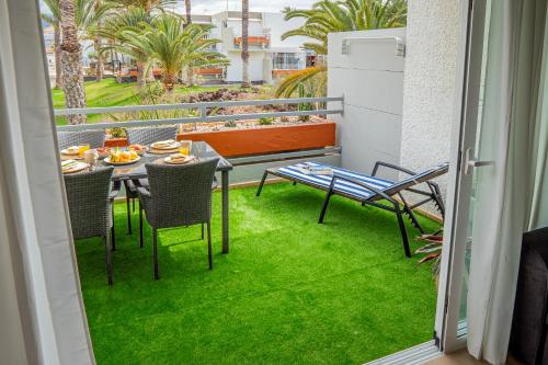 einen Balkon mit einem Tisch, Stühlen und Gras in der Unterkunft Relax studio Primavera in Las Galletas