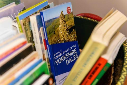 a group of books sitting on a shelf next to books at Finest Retreats - Shepherds Cottage at Mile House Farm in Hawes