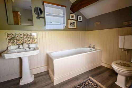 a bathroom with a tub and a sink and a toilet at Finest Retreats - Shepherds Cottage at Mile House Farm in Hawes