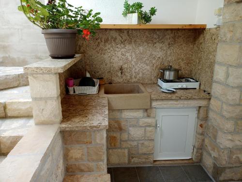 Una cocina de piedra con un fregadero y una olla en la pared. en Contessa robinson house, en Korčula