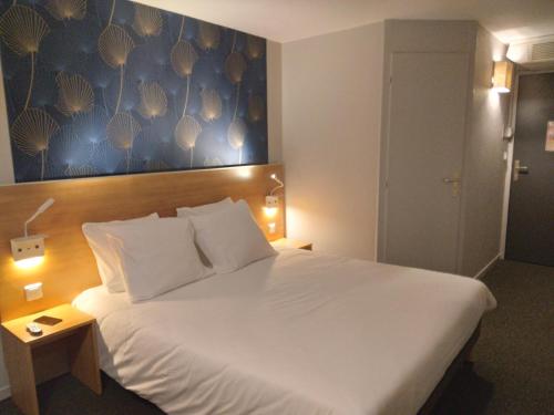 a bedroom with a large white bed with a blue wall at Cit'Hotel Hotel Prime - A709 in Saint-Jean-de-Védas