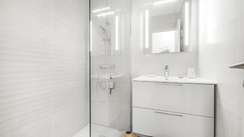 une salle de bain blanche avec une douche et un lavabo dans l'établissement L'AMARRE, Magnifique vue - hauteurs de Cavalaire, à Cavalaire-sur-Mer