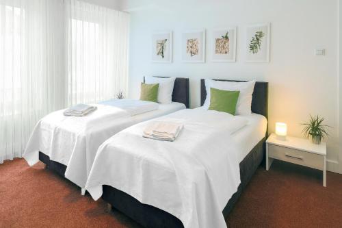 2 Betten in einem Zimmer mit weißer Bettwäsche in der Unterkunft Hotel Kleiner Markt in Saarlouis