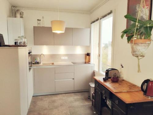 une cuisine avec des armoires blanches, un évier et une fenêtre dans l'établissement R'Apparts T2 Cosy et Vintage, à Grenoble
